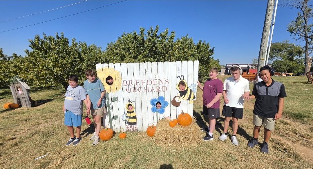 A group of young people pose at the Breeden's Orchard pumpkin patch sign.