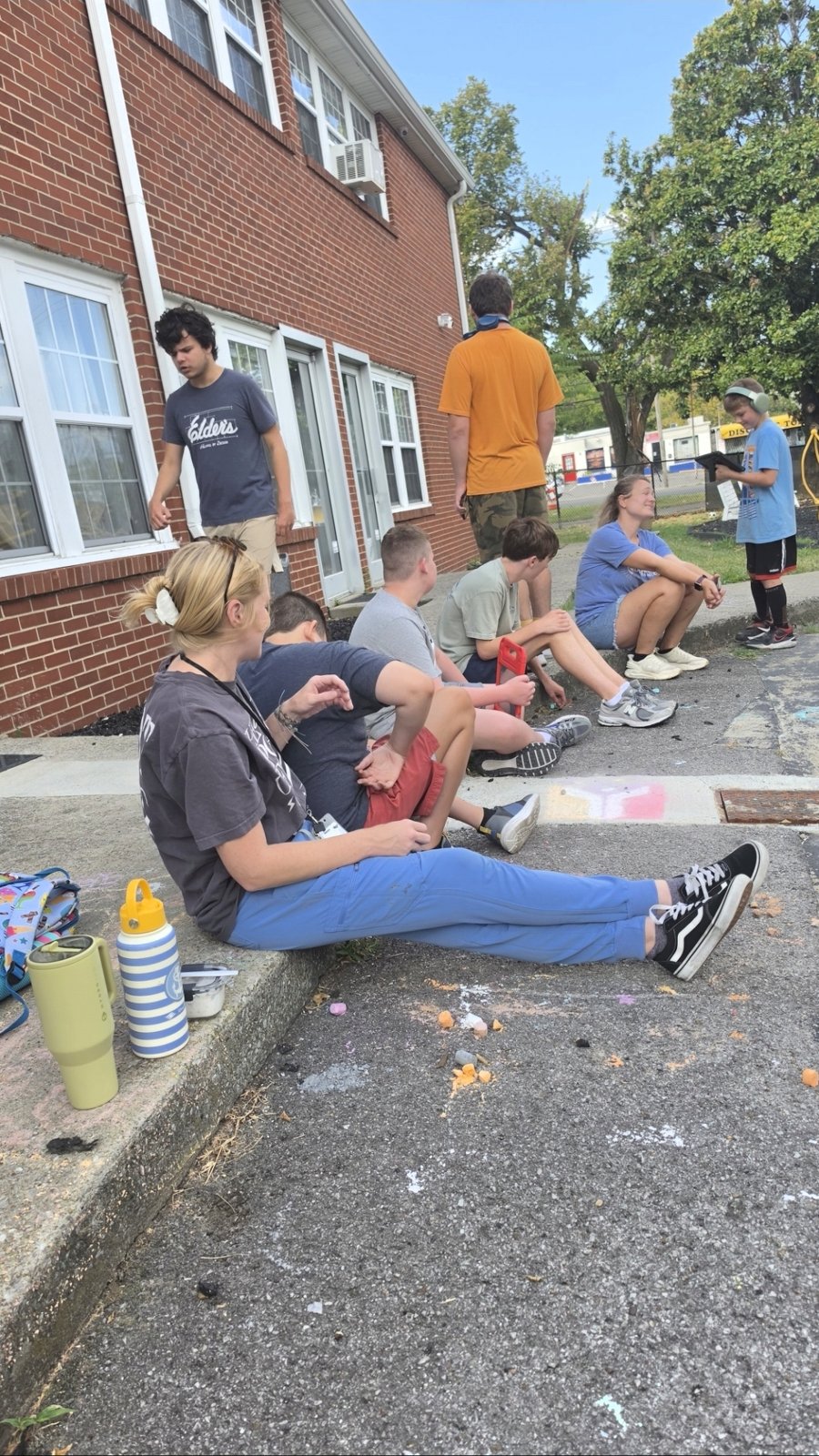 The group relaxes together on the steps outside the building.